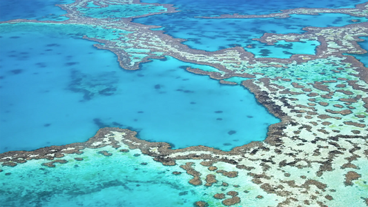 Aerial view of the Great Barrier Reef's turquoise lagoons and coral formations from above.